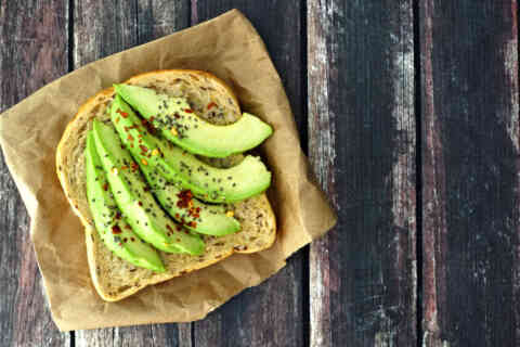 Open avocado sandwich on paper against rustic wood 506815964 1258x838