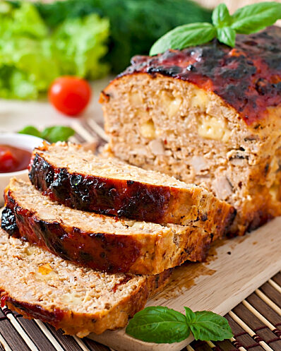 Meatloaf sliced on wooden board with ketchup and tomatoes 473174316 1259x836