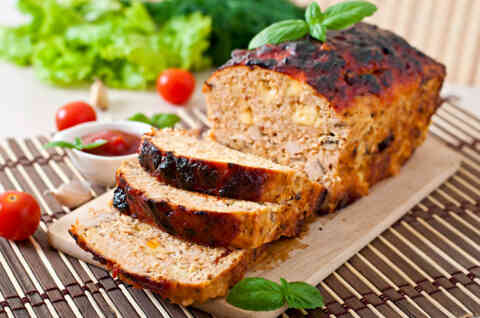 Meatloaf sliced on wooden board with ketchup and tomatoes 473174316 1259x836