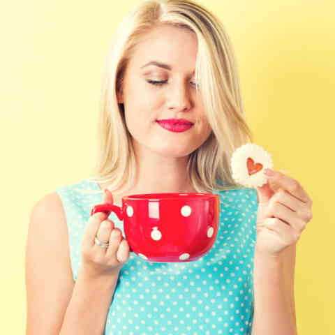 Happy young woman with cookie and coffee 827961646 1027x1027