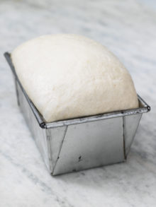 loaf of bread rising in a metal tin